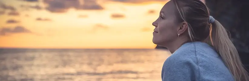 Woman smiling by the ocean to illustrate how one may feel once they overcome their anxiety with proper mental health treatment